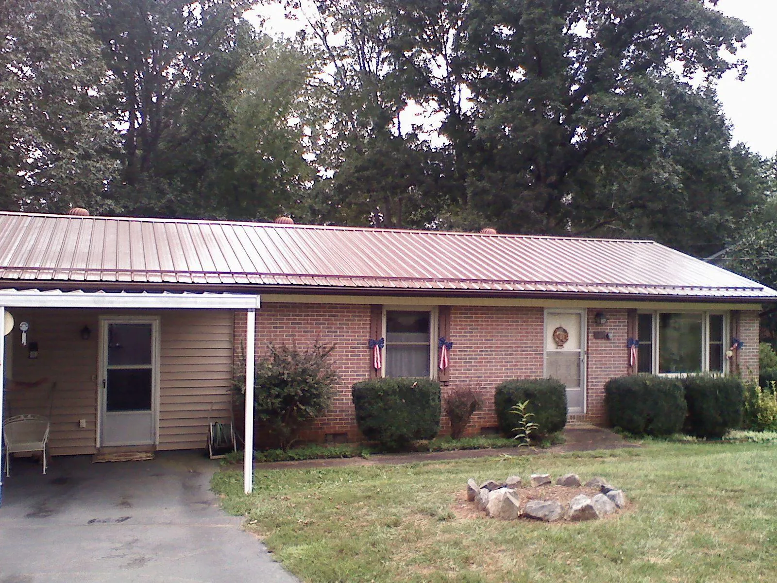 Bronze metal roof and carport on a brick ranch home — Roof Repair work by our crew in Shellsburg